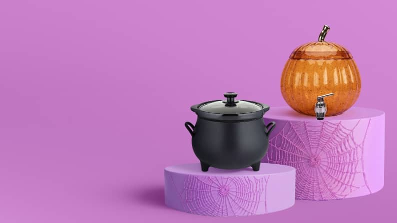 A black cauldron pot and an orange pumpkin-shaped drink dispenser sit on purple pedestals.