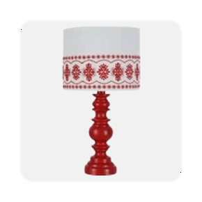Image shows a red turned table lamp with a white eyelet linen shade featuring red patterns, set against a light gray background.