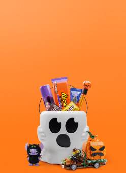 Reeses and other candy in a white ghost bucket with a purple character figurine and a toy car carrying a jack o lantern.