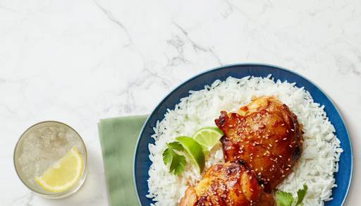 Glazed chicken and rice meals with lime and a side of lemon water.