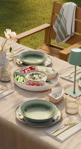 An outdoor table set with green bowls and a large divided serving tray filled with appetizers. Reads: Open-air hosting. From three twenty-eight.