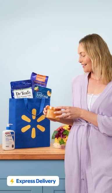 Walmart blue bag with spark logo holding electrolytes, skincare and bath soaks on a counter as a woman in a lavender robe holds a small jar.