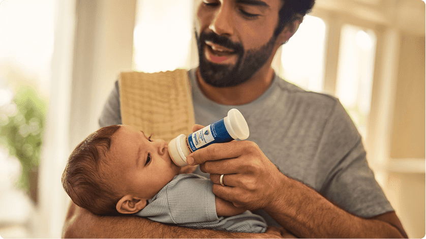 A father feeds his infant son with Similac baby formula.