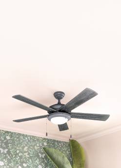 A grey ceiling fan in a green and pink room.