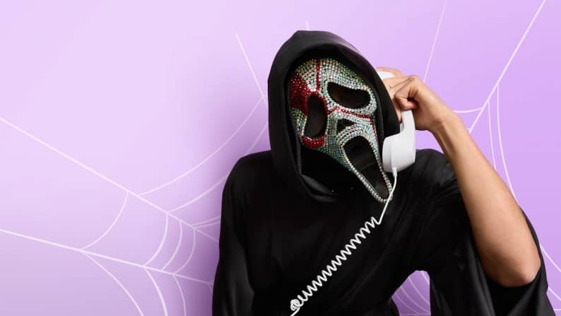 A person in a grim reaper costume holding a land-line telephone.