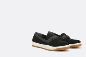 On-foot closeup of a pair of comfy yet stylish black loafers with faux leather details.