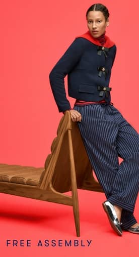 Woman in cropped navy jacket with oversized red collar over a red striped turtleneck, plus blue striped pants and silver flats.