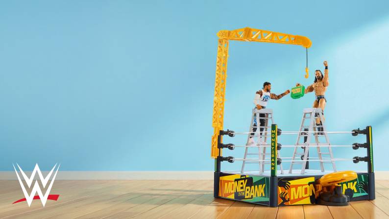 WWE logo. Two wrestling action figures on ladders in a toy ring with a crane, holding a briefcase.