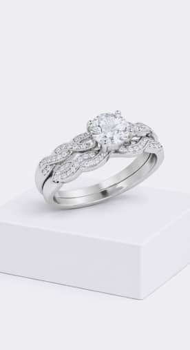A diamond wedding and engagement ring set sits on top of a white box.