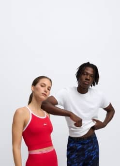 Two adults in casual athletic outfits, one in a red matching set and one in a white shirt with blue patterned shorts.