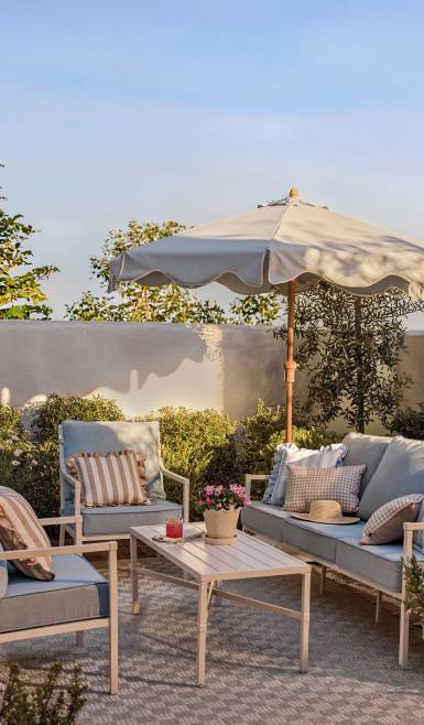 My Texas House patio furniture. Outdoor sofa and armchairs with cushions and decorative pillows, coffee table, outdoor rug and large umbrella.