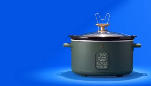Electric slow cooker with digital display reading two twenty two and touch controls, dark green body and glass lid with metal handle.