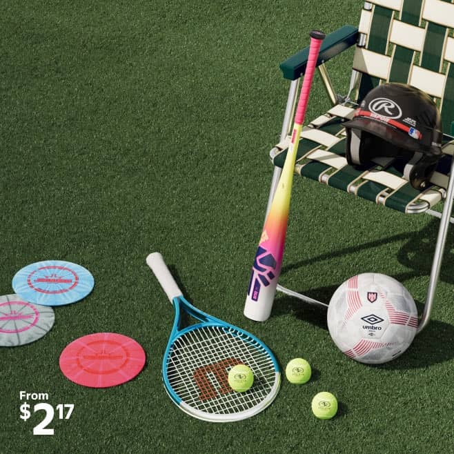 A lawn chair with a helmet on it, and a bat and soccer ball leaning up against it. Nearby lies a tennis racket, tennis balls, and golf discs.