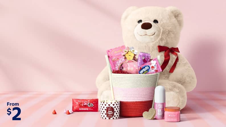 A plush bear, a basket with candy, fragrance and treats. Hershey’s Kisses, candle, fragrance and body scrub. Text reads: from two dollars.