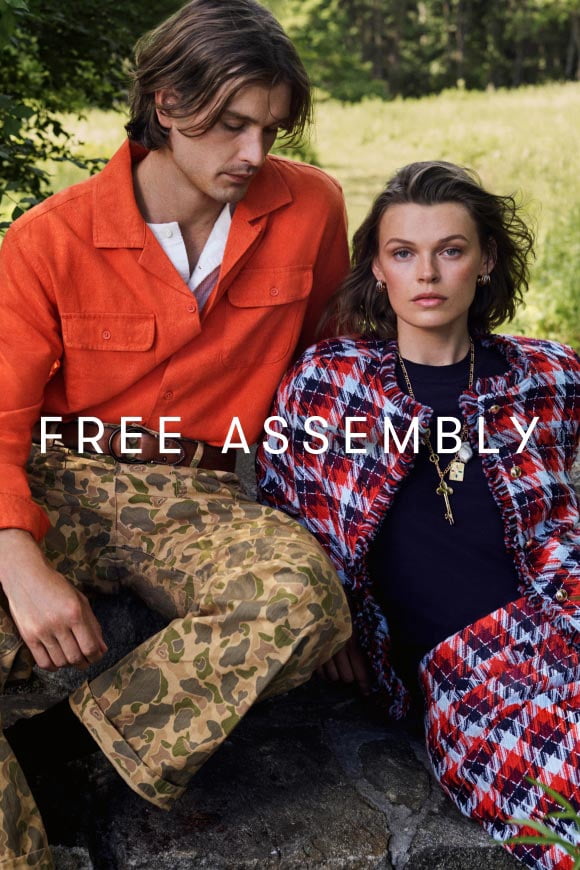 Man in an orange overshirt with camouflage pants sitting next to a woman in a red, white and blue tweed jacket and matching skirt.