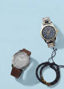A brown watch, silver watch, black bracelets.