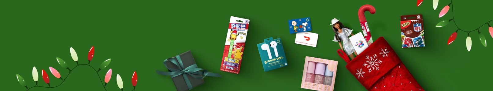 A present, Pez dispenser, wireless earphones, a mist set, gift cards, a stocking with a Barbie, a candy cane, and Uno cards.