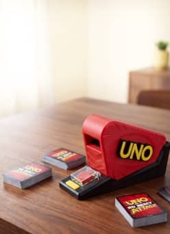 Uno card shooter and Uno card decks on a wooden table.