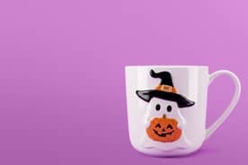 Halloween-themed mug featuring ghost wearing a witch’s hat holding a jack o lantern.