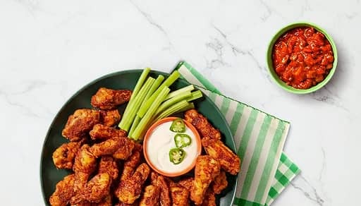 A large platter of crispy chicken wings is displayed with a white dipping sauce.