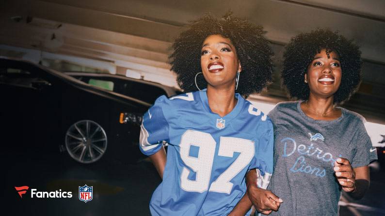 Two women are shown. Woman on left wears a Detroit Lions jersey and woman on right wears a Detroit Lions graphic tee. Fanatics and NFL logos are seen.