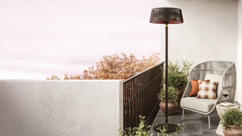 Modern patio with tall outdoor heater, chair, fall pillows & planters.
