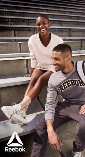 Reebok logo. Two people wearing Reebok activewear are pictured sitting on cement bleachers.