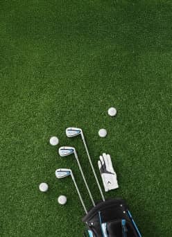 Golf clubs, balls, and gloves spill out of a golf bag onto the green