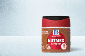 Image shows a clear bottle with red and black lid containing McCormick ground nutmeg on a light blue textured background.