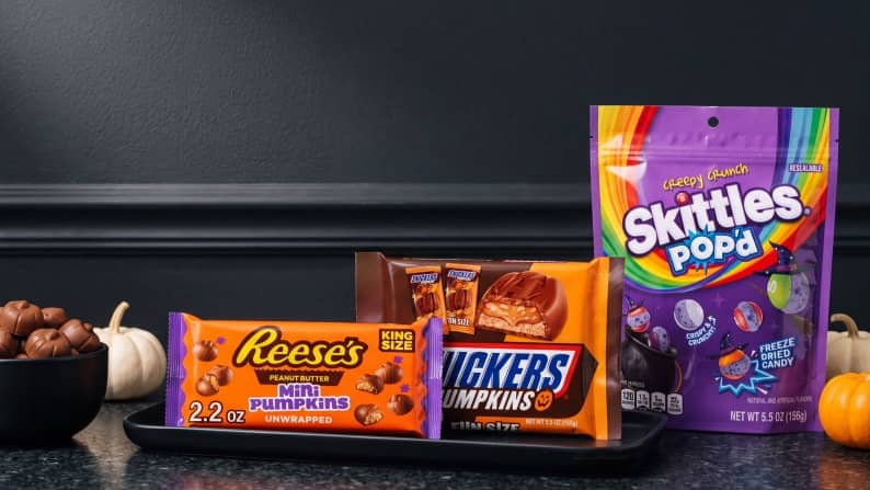 A bag of Reese’s mini pumpkins, Snickers pumpkins and Skittles Pop’d is shown.