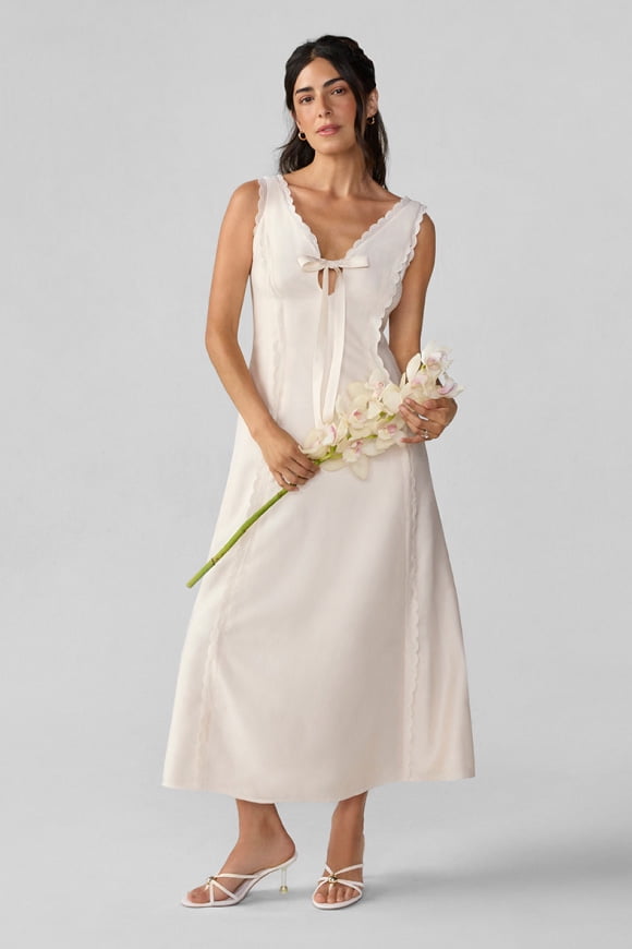 An image of a woman wearing a white summer dress from our bridal curation.