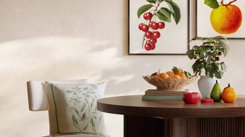 White floral pillow on a chair by a table with botanical accents, wicker lamp and tomato candle. Reads: Stylish by nature from nine seventy-eight.