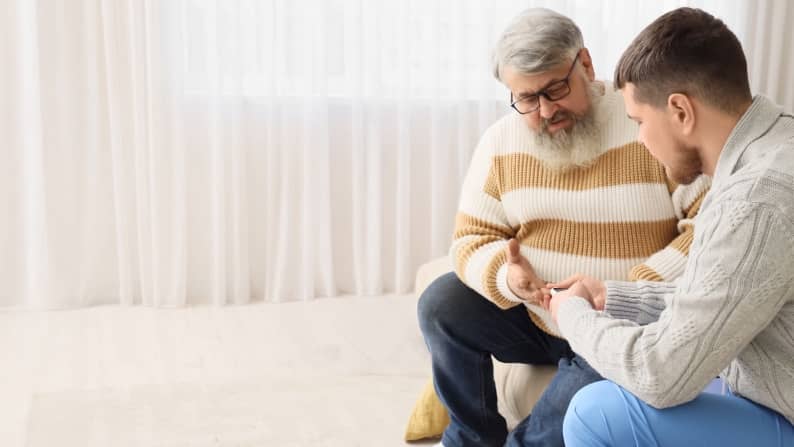 Caregiver assisting senior patient with an at-home diabetes test.