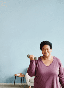 A woman wearing a purple shirt, exercising with hand weights as part of her weight management plan.