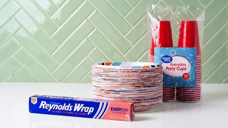 Reynolds Wrap Everyday foil box with patterned disposable plates and Great Value Everyday Party Cups fifty count on a white surface.