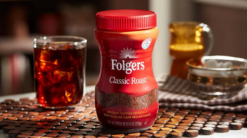 A canister of Folgers Classic Roast coffee in front of an iced coffee.