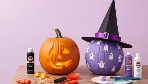 An orange carved pumpkin, a purple pumpkin with painted ghosts, and craft materials.
