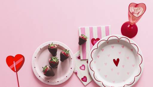 Plate, napkins, heart-shaped cup and chocolate-covered strawberry.