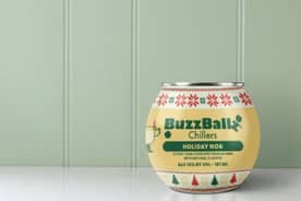A BuzzBallz chillers holiday nog cocktail on a white counter against a light green background.