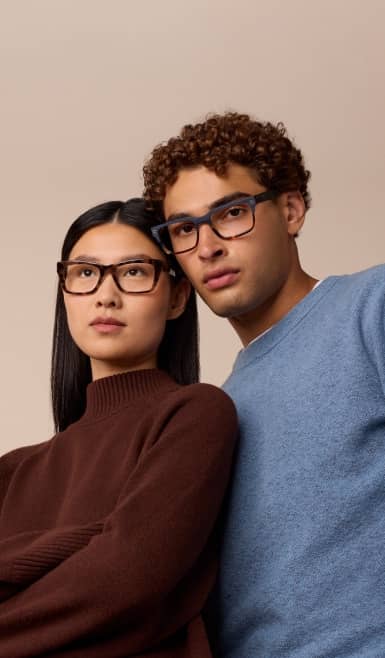 Two adults wearing modern eyeglasses pose closely together.