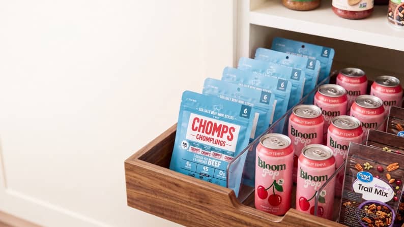 Chomps Chomplings beef sticks, Bloom Pop cherry cans and a Great Value Trail Mix bag organized in a wooden pantry drawer.