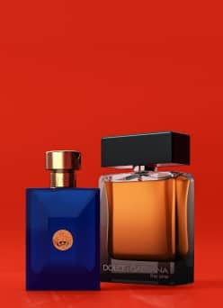 A product shot of two cologne bottles. The first bottle is a blue Versace bottle and the second bottle is a Dolce & Gabbana bottle.