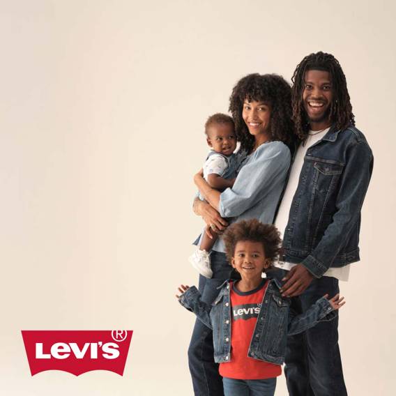A smiling family wears denim outfits. The mom holds a baby, the father wears a jean jacket and a child in front wears a red Levi’s shirt and jacket.