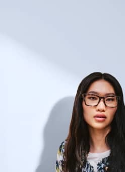 Adult wearing prescription eyeglasses and a floral top.