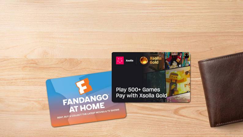 Gift cards on a wood table next to a brown wallet.