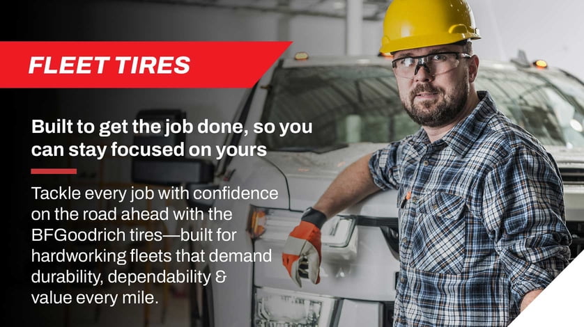 A construction worker leans against a construction truck.