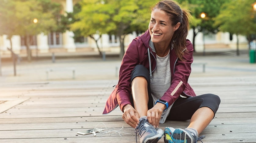 Woman lacing up her shoes outside.