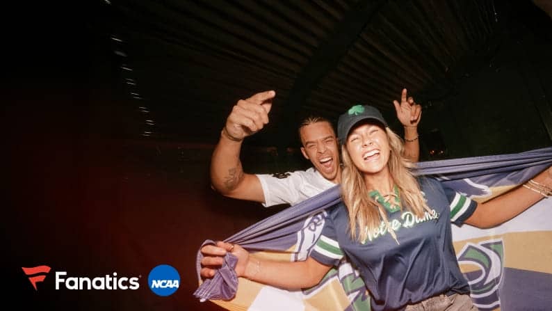 A young man and woman are cheering. The woman wears a Notre Dame flag and gear. Fanatics and NCAA logos are shown, all on a black background.