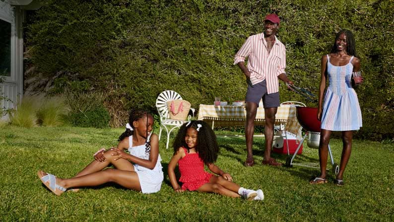 A family of four is wearing red, white and blue outfits on the lawn together.