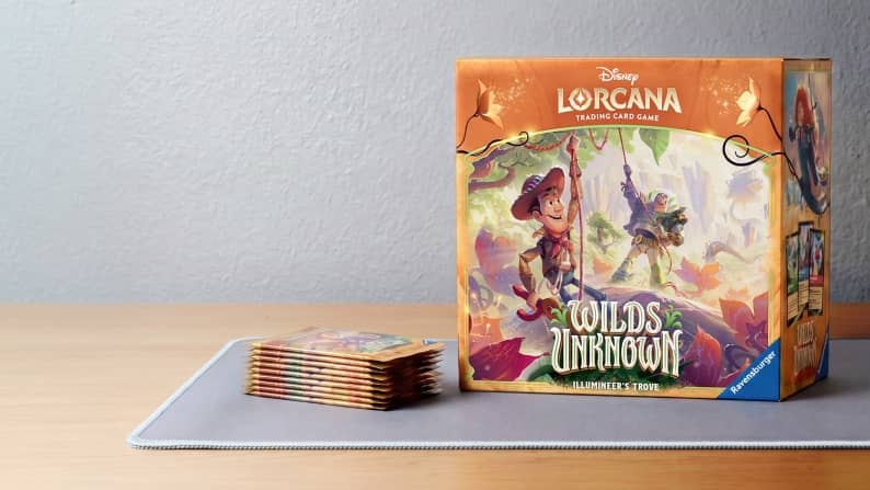 A box case of Lorcana Wilds Unknown next to a neat stack of cards from the Wilds Unknown set.